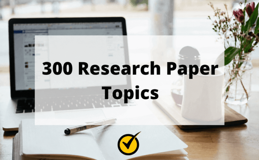 Open laptop, open notebook with pen, and flowers on a desk; text overlay reads "300 Research Paper Topics" with a yellow checkmark symbol at the bottom.